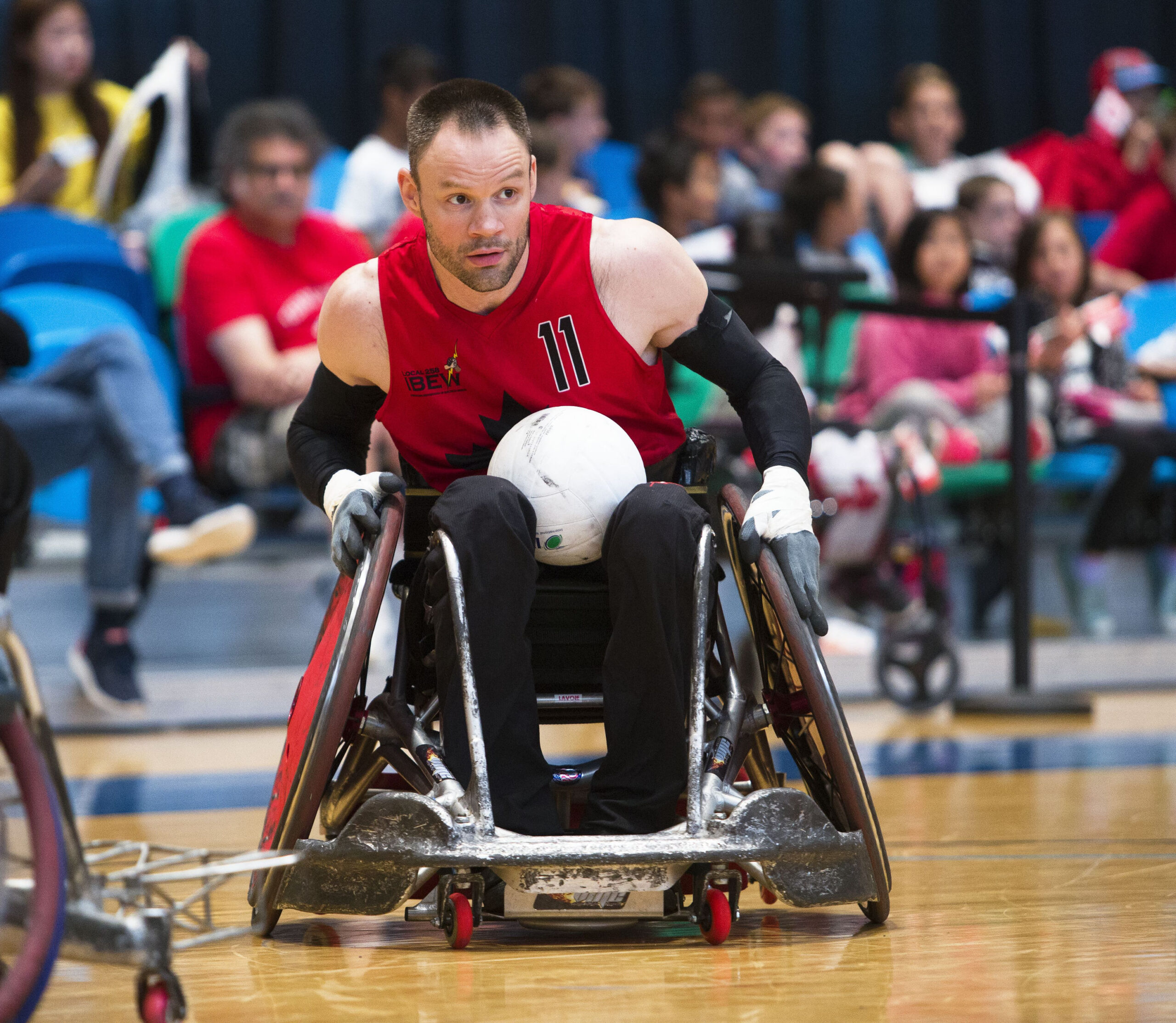 A wheelchair rugby player, Fabien Lavoie, holding a ball while seated in his wheelchair.